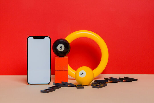 Smartphone with fallen dominoes and billiard balls
