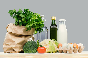 Delivery of grocery. Bag with fresh vegetables bright green dairy eggs produce on table. Eco...