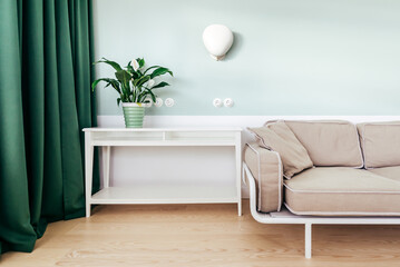 A brown couch next to a table and a potted green plant