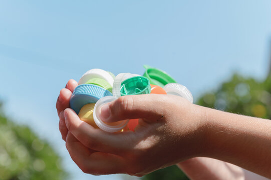 Child Holding Handful of Collected Plastic Bottle Caps