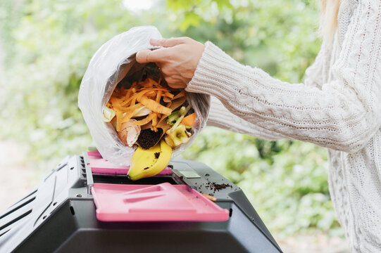 Throwing Food Waste Scraps into a Tumbling Compost Bin