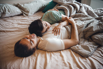The image of a couple sleeping in bed embracing. Pretty young family.