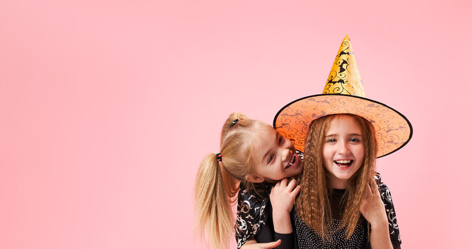 Vampire girl trying to bite witch girl on pink background