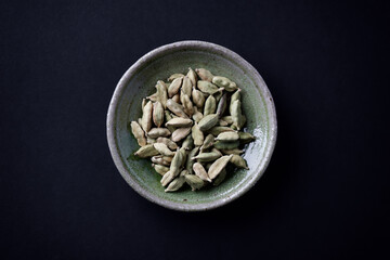 Green Cardamom Seeds on dark paper background. Top view. Close up. Copy space. 