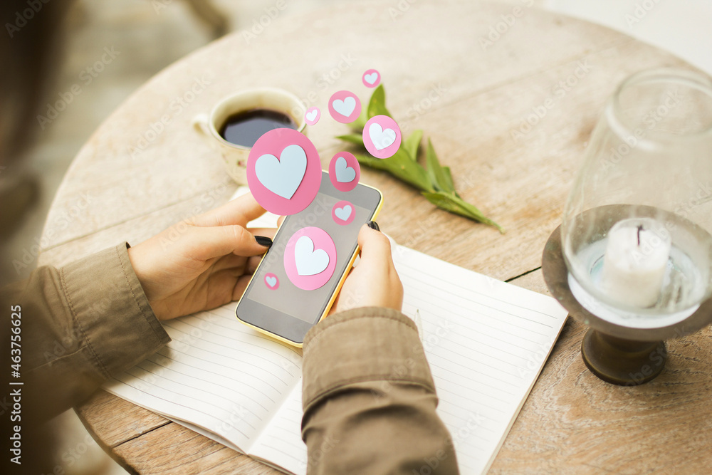 Poster close up and top view of female hands using smartphone with abstract hearts on blurry background wit