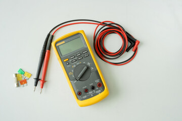 Yellow Digital multimeter with probes on white background , A multimeter is an electronic measuring...