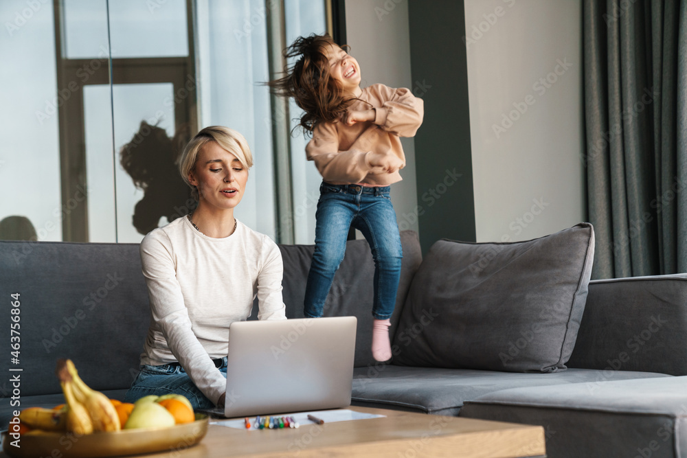 Canvas Prints Happy young blonde mother working on laptop computer