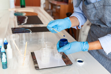 Fototapeta premium Mixing process of two resin components for creativity, close-up, gloved hands, resin art master class