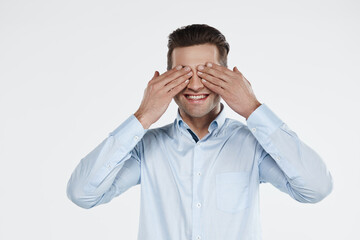 Naklejka premium Young smiling european business man covering eyes