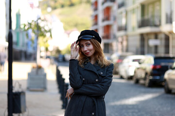 Obraz premium Woman in black beret and coat in the street