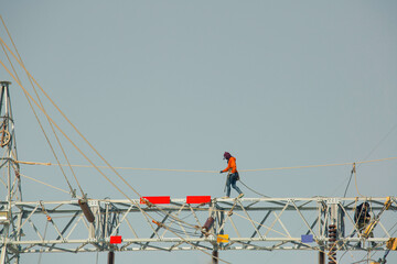 Male walking on the beam steel Installation of high-voltage  transmission electricity poles