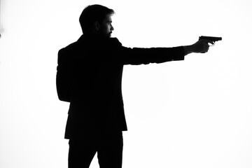 The man in a suit gun in the hands of the emotions silhouette posing studio