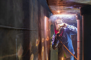 Fototapeta premium Welding male worker metal arc is part in machinery tank nozzle pipeline construction tank oil inside confined spaces.