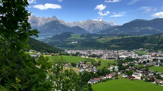 Panning shot of pictureque rural cityscape with mountain range in background during sunny day - Bischofshofen,Austria