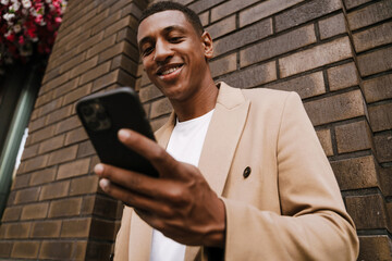 Young black man using mobile phone while standing at city street