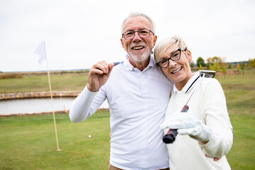 Portrait of retired senior people with golf clubs playing their favorite sport game and enjoying...