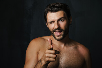 Young half-naked man winking while pointing finger at camera