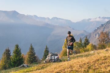 Fototapeta na wymiar Athlete man runs through mountain meadows in autumn.