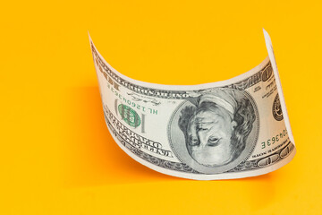 Single Hundred Dollar Bill Curled on yellow