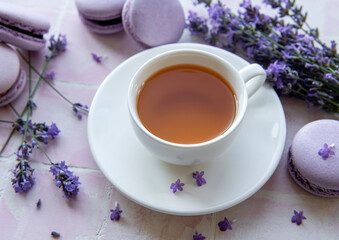 Fototapeta na wymiar Cup of tea with macaroon dessert with lavender flavor