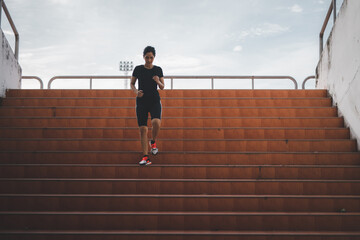 A beautiful woman runner is jogging up the steps under the sunlight. The concept of stepping into success, self-improvement in exercise.