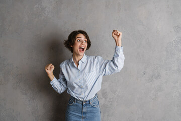 Young brunette woman making winner gesture and screaming