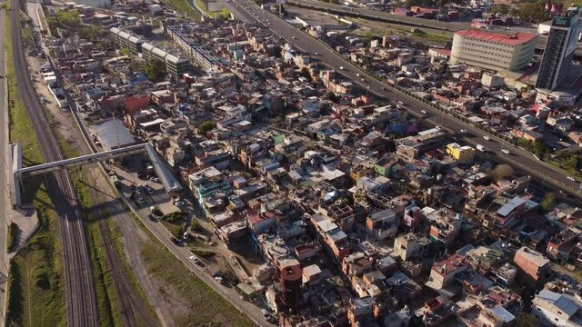 Aerial flyover poor slums neighborhood surrounded by rail tracks and highway road in Buneos Aires