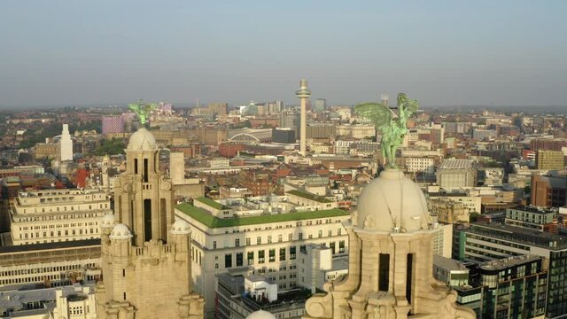 Liverpool city skyline at sunset with cinematic drone movement past famous liver building.