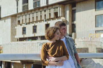 Love story of stylish funny couple: young man in a t-shirt. And a cute young woman in wedding white skirt and yellow sweater. Family holiday and togetherness, date.