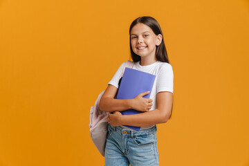 White brunette girl smiling while posing with backpack and exercise book - obrazy, fototapety, plakaty