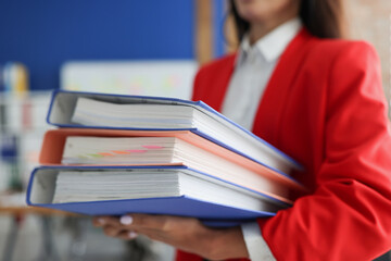Woman holding a stack of folders with documents