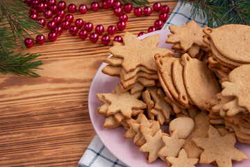 full plate of homemade freshly made gingerbread cookies on wooden background. Christmas tree decorations on the table. Classic traditional Christmas cookies with spices, cinnamon, cumin and ginger