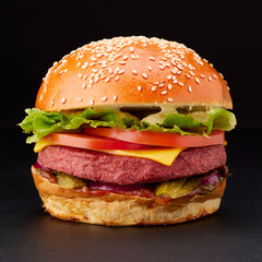 Delicious vegetarian burger with vegetable cutlet, cheese and vegetables on black background.