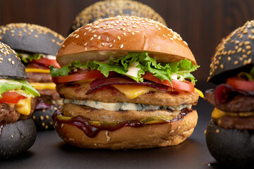 Yummy grilled beef burgers on a wooden background, side view. Takeaway hamburger, fast food.