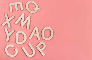 Wooden alphabet letters on pink paper background.