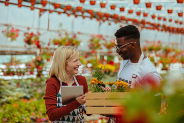 Young florist couple working in greenhouse via technology