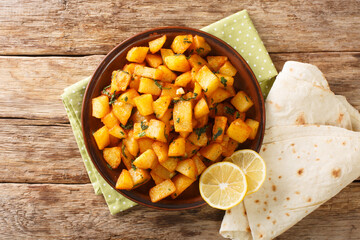 Lebanese spicy potatoes are traditionally known as batata harra close up in the plate on the table. Horizontal top view from above