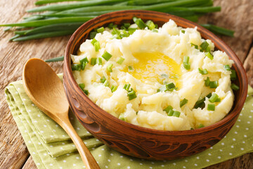 Irish Champ is a simple food made of potatoes, milk, green onions, butter close up in the bowl on the table. Horizontal
