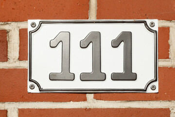 Hausnummernschild Nummer Einhundertelf, Backsteinmauer, Deutschland