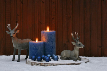 Weihnachtsdekoration: Blaue Kerzen mit zwei Hirschen im Schnee.