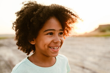 Black curly boy wearing t-shirt smiling and looking aside