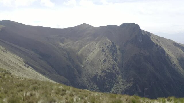 Drone shot moving forward and then down over the moorlands of the Andes in Rucu Pichincha near Quito Ecuador. Mountains and vegetation are seen.