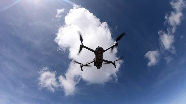 Slow motion of a DJI Mavic Pro 2 drone taking off to fly during a sunny day with blue sky and some clouds.