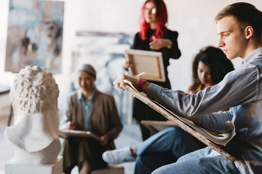 Young multiracial students drawing plaster bust in art school