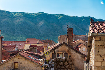 Fototapeta na wymiar Panoramic view of the orange tiled roofs of the old town of Kotor in Montenegro against the backdrop of green mountain slopes. The houses have retained the unique atmosphere of antiquity