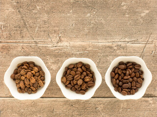 Fototapeta na wymiar Light Roast, Medium Roast and Dark Roast Coffee Beans on Brown Weathered Wood