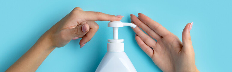 Womans hands use hand sanitizer or soap on blue background