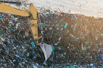 Excavator sorting metals for recycling at a recycling center, vertical image.