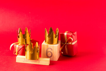 Dia de Reyes Magos day ( Three Wise Men) or Epiphany day concept. Three gold crowns on red background with 6 Junuary date  and gifts
