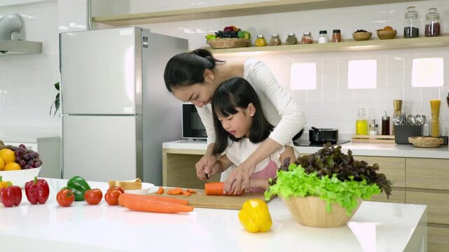 Pregnant woman and daughter cooking in kitchen room at home. Asian family cooking at home. Concept food and cooking healthcare.